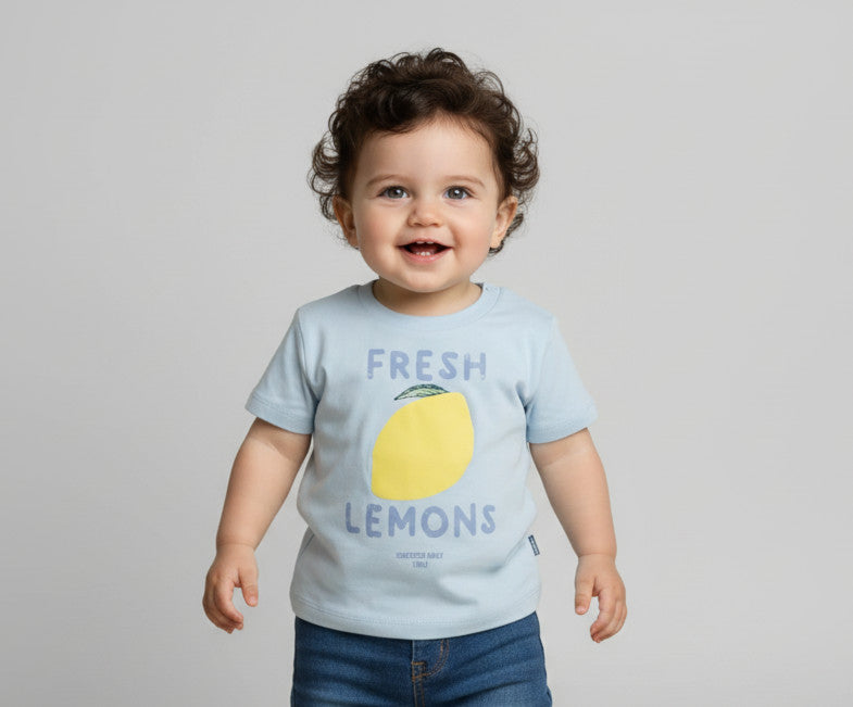 Child wearing a light blue t-shirt with a lemon graphic and text on a plain background